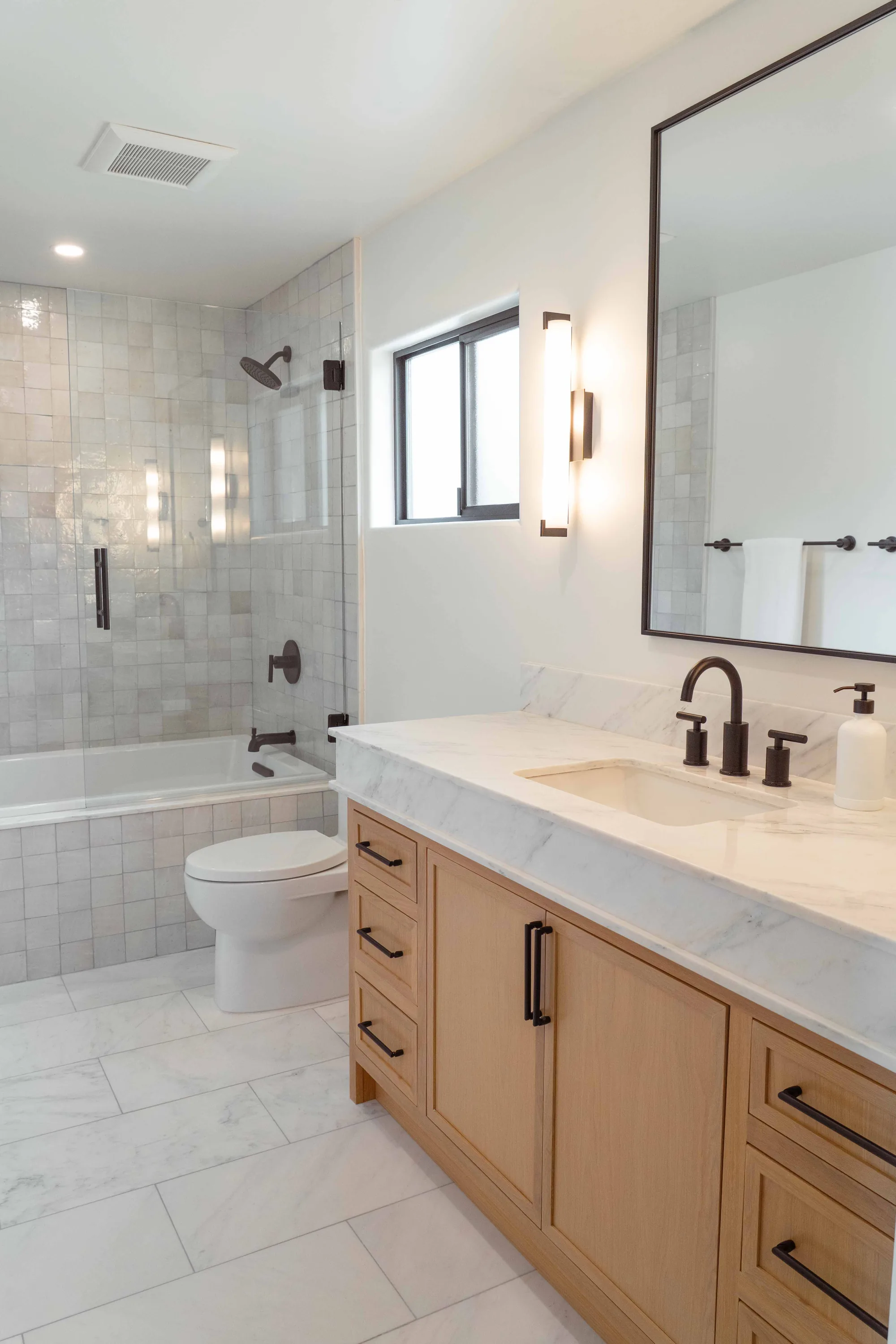 Bathroom remodel in Solana Beach with white oak vanity, Calacatta marble countertop, zellige tile shower, and matte black fixtures