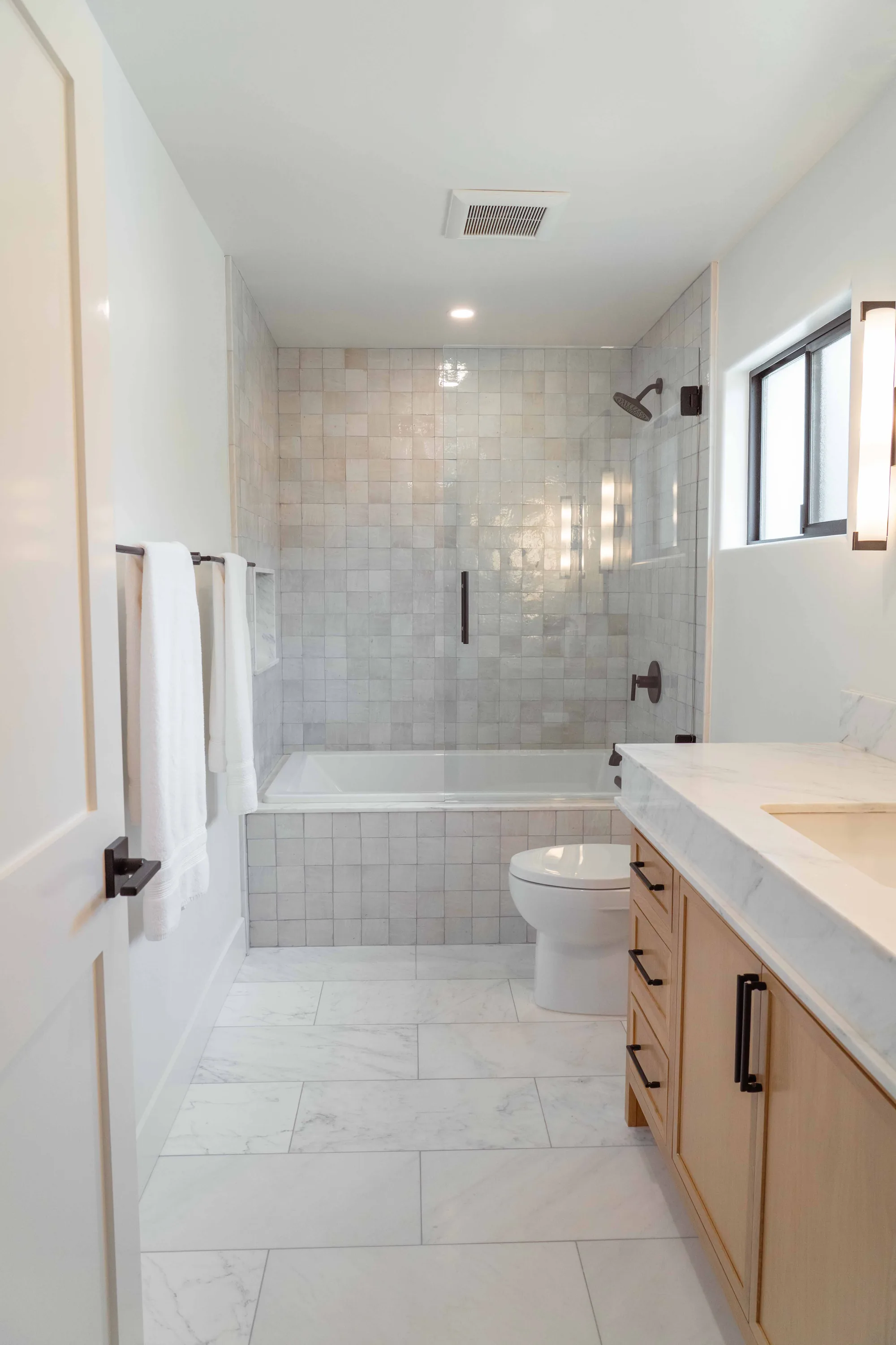 Full bathroom layout showing tub-shower combination with zellige tile walls, frameless glass door, and marble floor tile