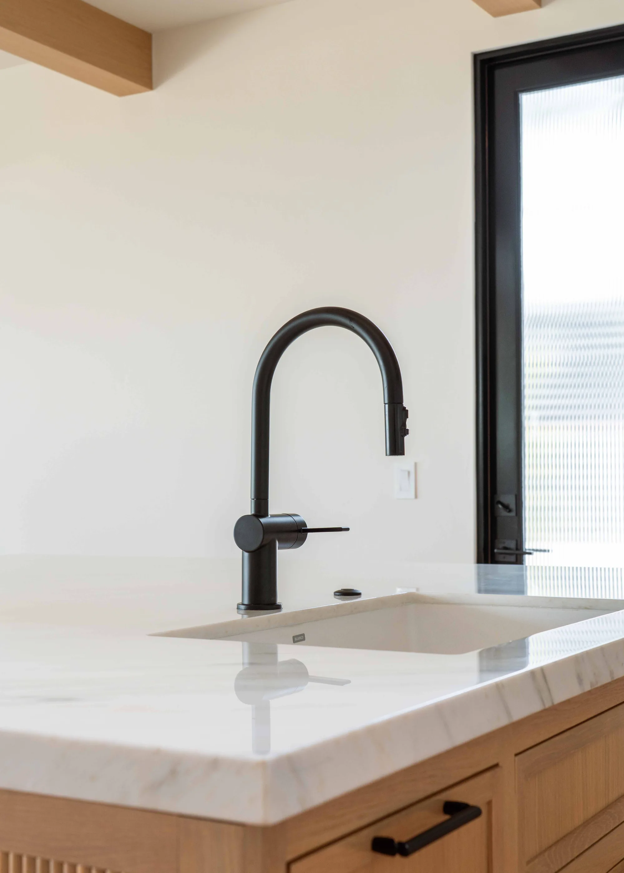 Kitchen island detail with undermount sink, matte black pull-down faucet, and quartz countertop in Solana Beach