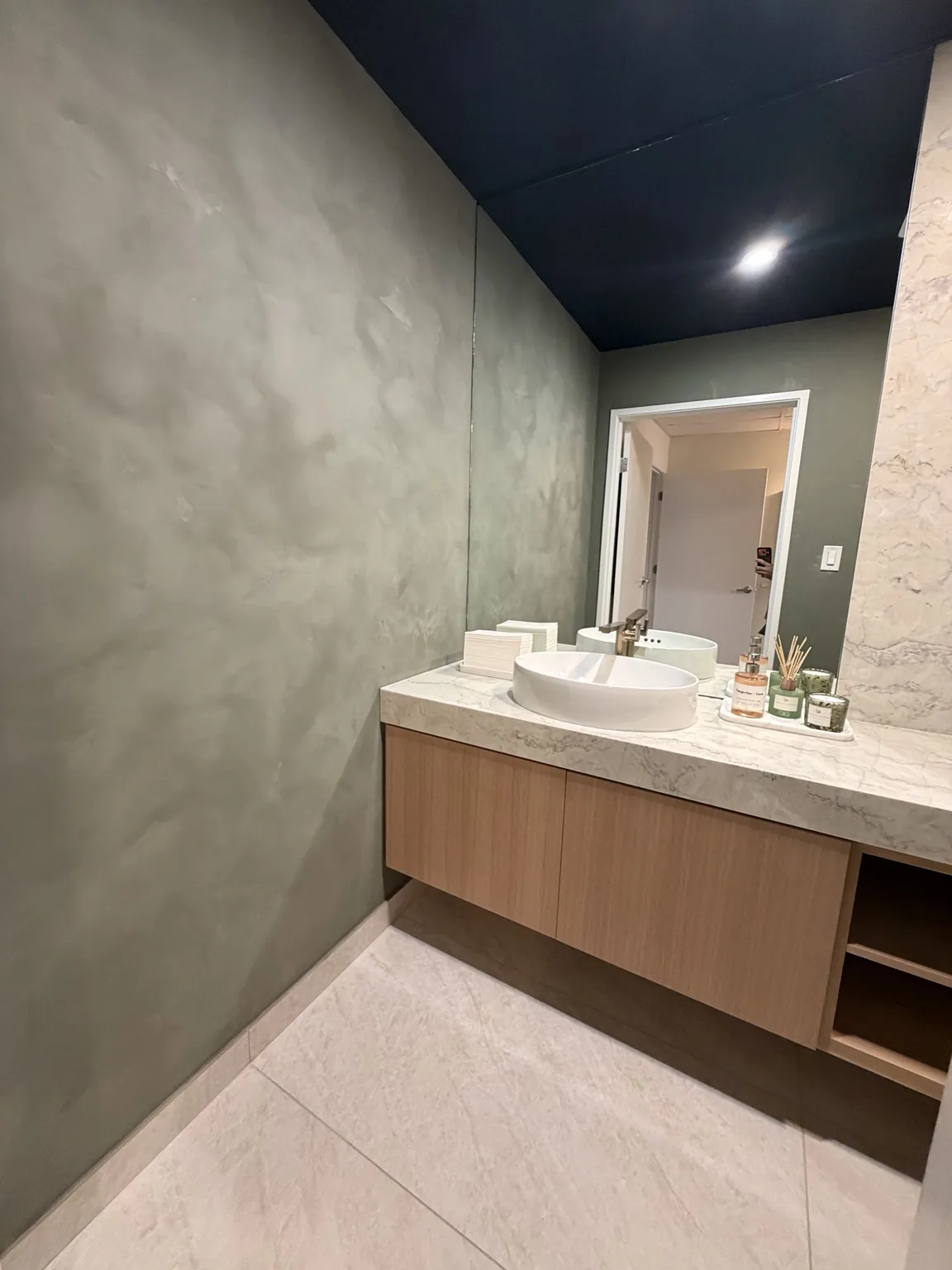 Powder room with a floating oak vanity, stone countertop, vessel sink and plaster walls