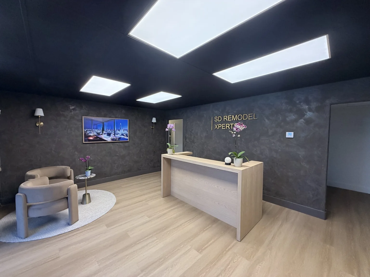 Design Center reception with a light oak desk, lounge chairs and textured charcoal walls