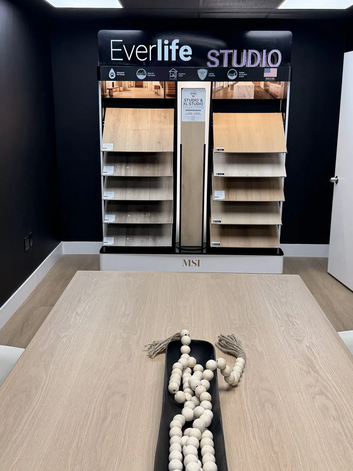 Flooring sample display with light wood-look planks behind a meeting table