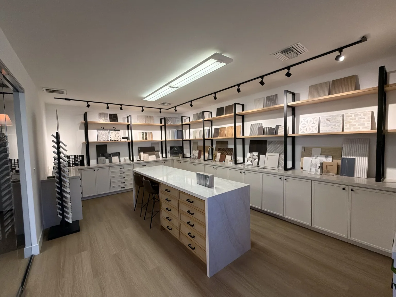 SD Remodel Experts Design Center materials studio with tile, stone and wood samples on open shelving around a marble island